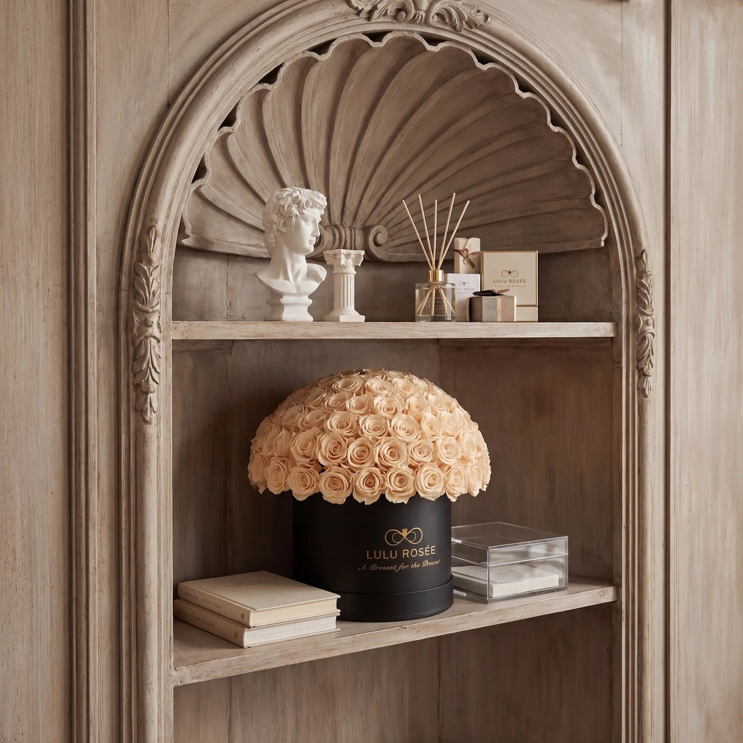 Decorative shelf with a shell sculpture, bust, and LULU ROSEÉ product.
