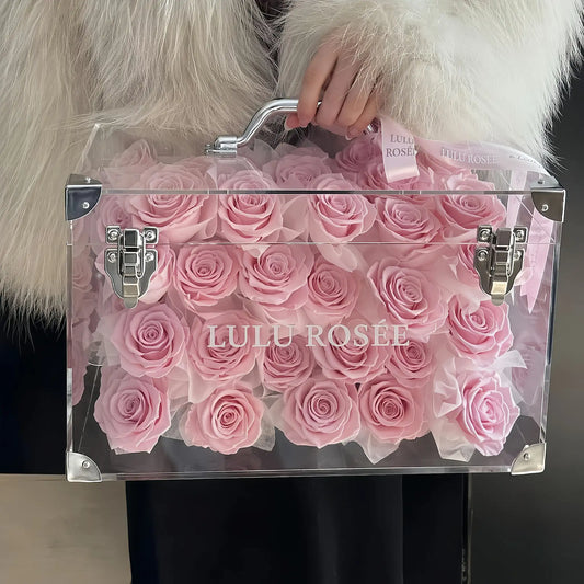 LULU ROSÉE Moyenne Eternal Acrylic Handbag Rose Box, medium transparent acrylic handbag-shaped gift box filled with blush pink preserved roses, soft fur background front full shot, customizable flower colors, elegant everlasting floral gift for birthdays, anniversaries & romantic celebrations