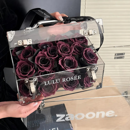 LULU ROSÉE Petite Eternal Acrylic Handbag Rose Box, small transparent acrylic handbag-shaped gift box filled with dark purple preserved roses, open lid detailed close-up view, customizable flower color options, mini luxury everlasting floral souvenir for birthday, anniversary & romantic gift giving